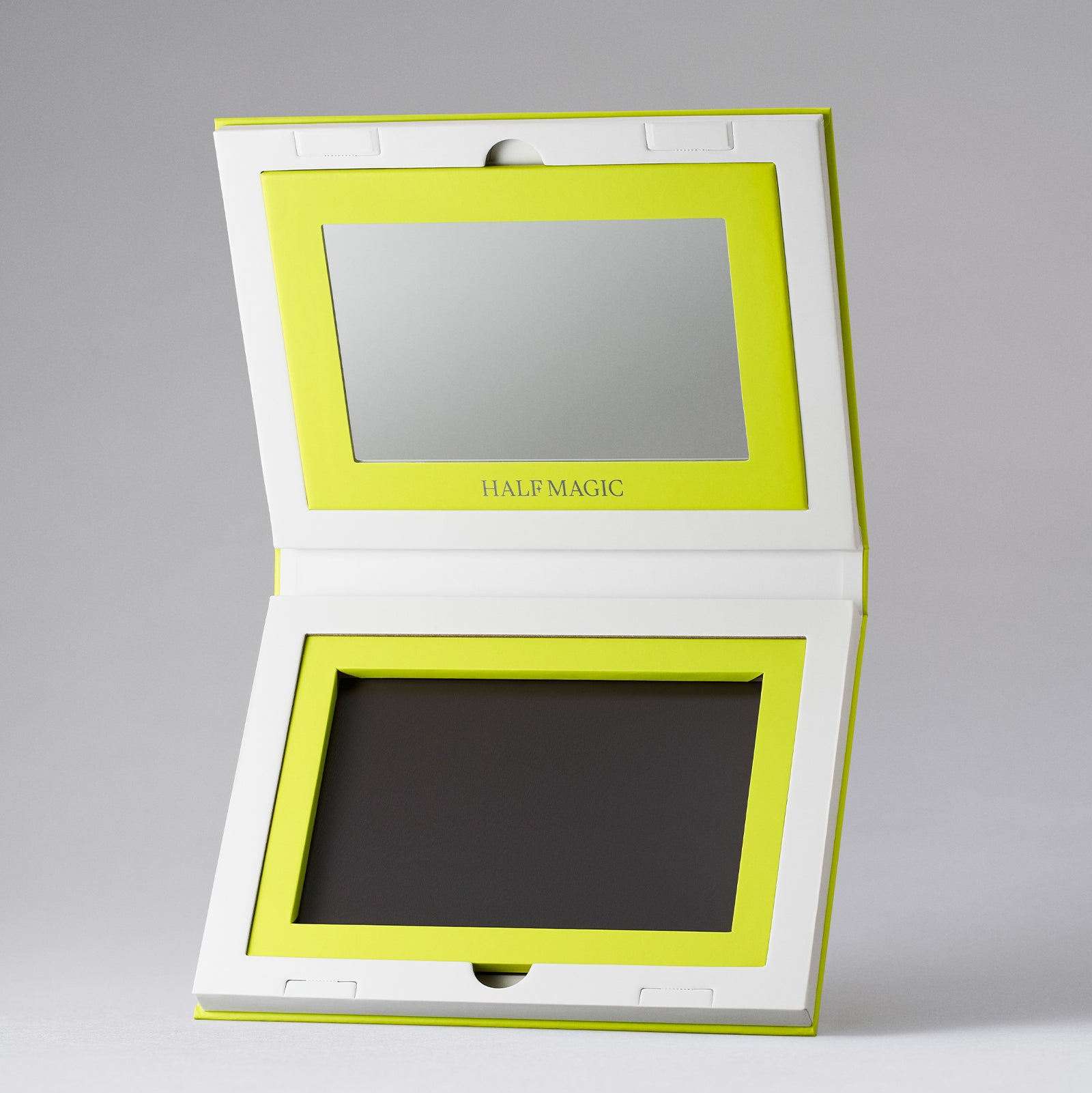 The Forever Palette open. Compact mirror with green frame and 'HALF MAGIC' branding on a gray background